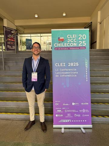 Professor Marcelo em frente ao poster do evento